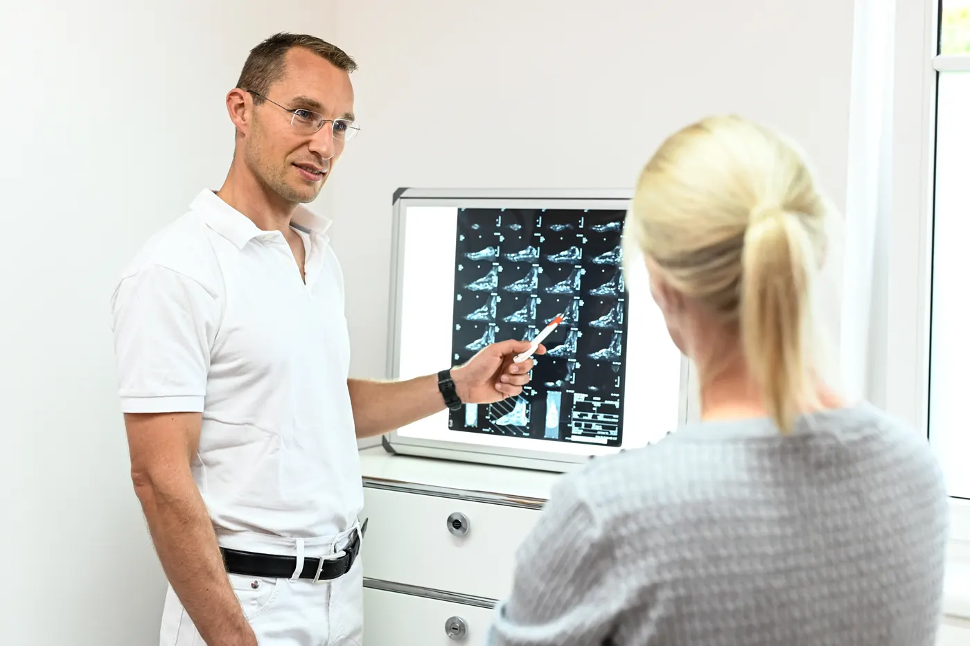 Priv.-Doz. Dr. Lukas Zak erklärt einer Patientin ihre Röntgenbilder