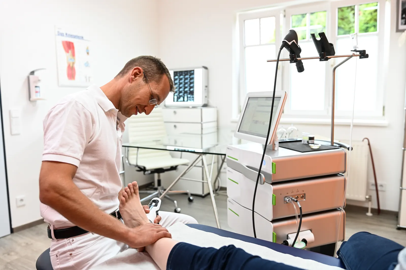 Priv.-Doz. Dr. Lukas Zak behandelt den Fuß einer Patientin mit Stoßwellentherapie